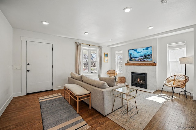 living area featuring recessed lighting, a fireplace with flush hearth, baseboards, and wood finished floors