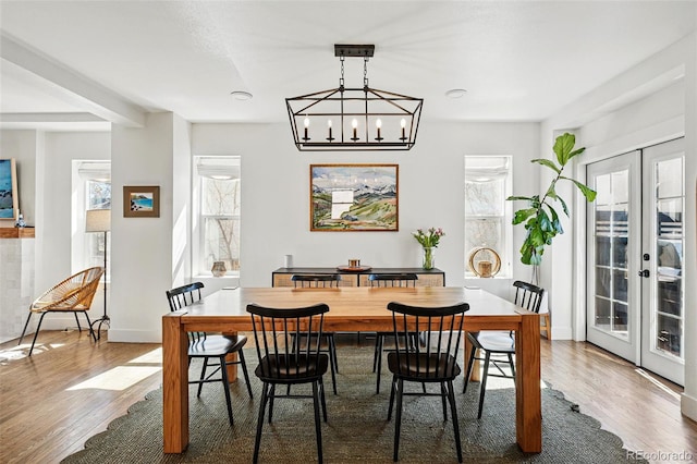 dining room featuring a chandelier, french doors, wood finished floors, and baseboards