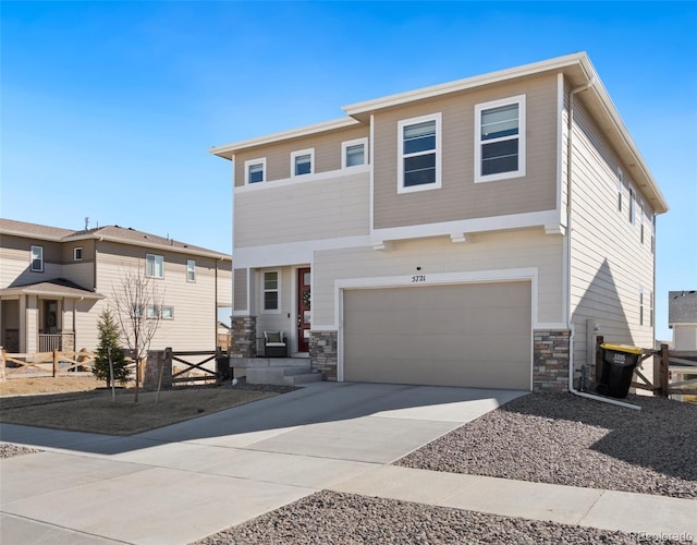 view of front facade with driveway, stone siding, a garage, and fence