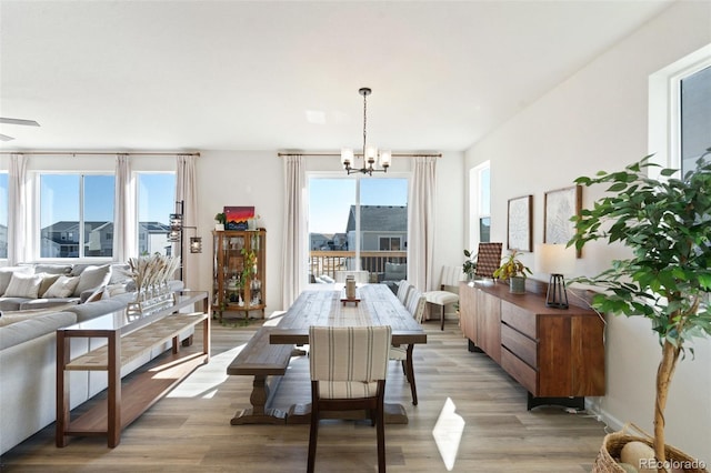 dining area featuring baseboards, light wood-type flooring, and an inviting chandelier