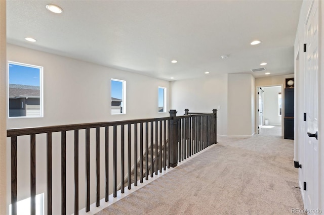 hall with visible vents, baseboards, carpet, an upstairs landing, and recessed lighting