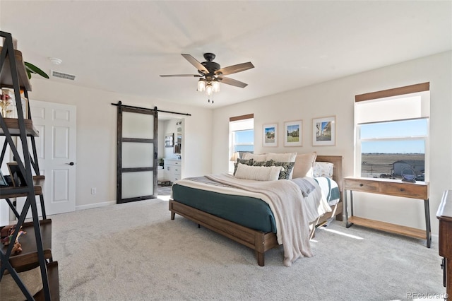 carpeted bedroom with a barn door, visible vents, ceiling fan, and baseboards