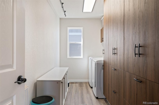 washroom with cabinet space, baseboards, washer / clothes dryer, and light wood-style floors