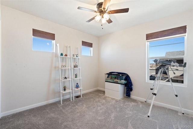 interior space featuring carpet floors, multiple windows, ceiling fan, and baseboards