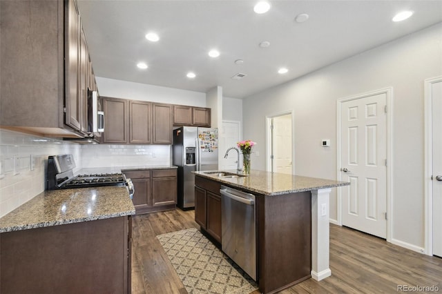 19221 E 65th Ave, Denver, CO 80249 - kitchen with appliances with stainless steel finishes, tasteful backsplash, dark wood finished floors, light stone counters, and recessed lighting