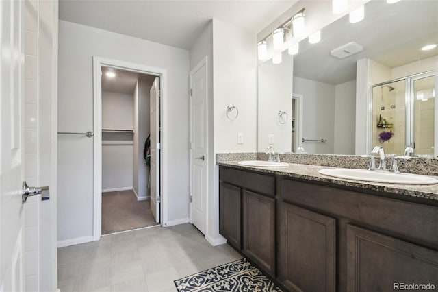 19221 E 65th Ave, Denver, CO 80249 - bathroom featuring double vanity, a shower stall, tile patterned floors, and a spacious closet