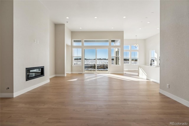 unfurnished living room featuring light hardwood / wood-style floors, a wealth of natural light, and a notable chandelier