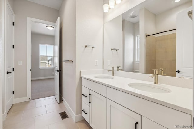 bathroom with tile patterned floors, vanity, a tile shower, and toilet