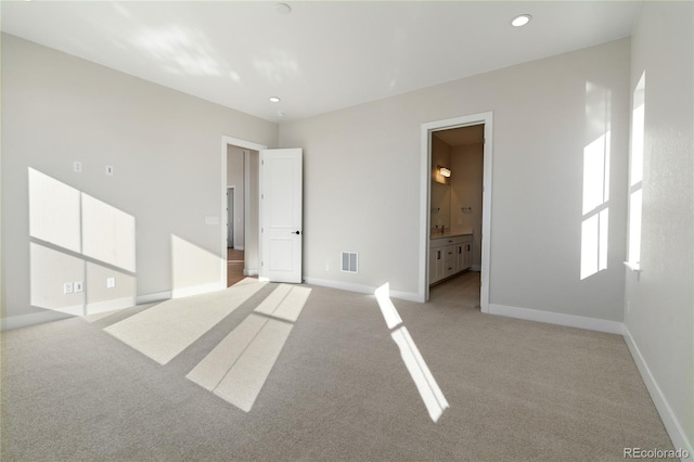 interior space featuring ensuite bathroom and light colored carpet