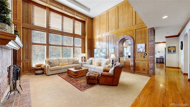 carpeted living room with a towering ceiling, ornamental molding, and a fireplace