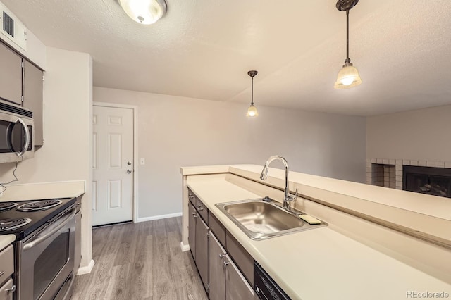 8853 Colorado Blvd Unit A-106, Thornton, CO 80229 - kitchen featuring a sink, appliances with stainless steel finishes, light wood-style flooring, hanging light fixtures, and light countertops