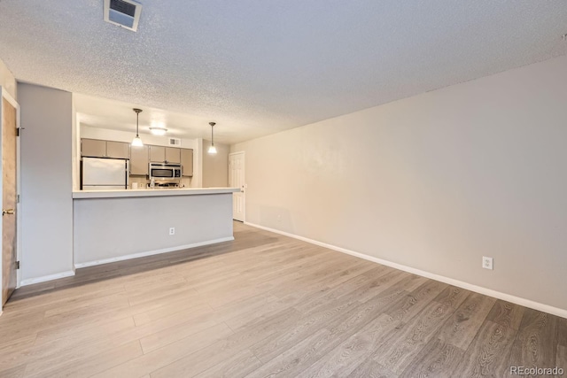 unfurnished living room featuring light hardwood / wood-style flooring and a textured ceiling