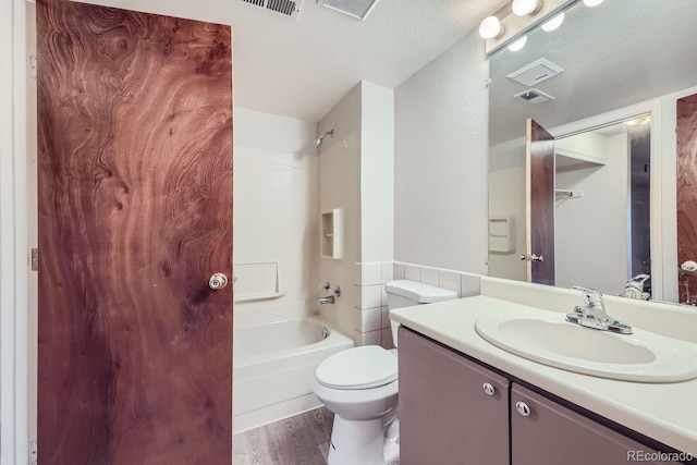 full bathroom featuring wood-type flooring, shower / bathing tub combination, a textured ceiling, toilet, and vanity