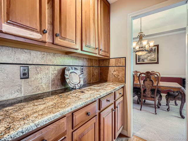 6577 S Waco Way, Aurora, CO 80016 - kitchen with a chandelier, light stone countertops, backsplash, light colored carpet, and brown cabinets