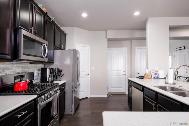 kitchen featuring a sink, light countertops, appliances with stainless steel finishes, decorative backsplash, and dark wood finished floors