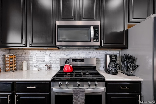 kitchen with stainless steel appliances, dark cabinetry, and light countertops