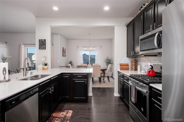 kitchen with stainless steel appliances, a sink, light countertops, dark wood-style floors, and tasteful backsplash