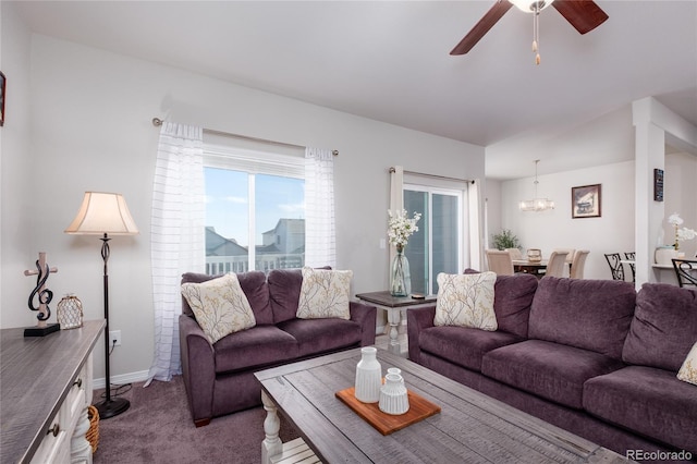 carpeted living room with baseboards and ceiling fan with notable chandelier