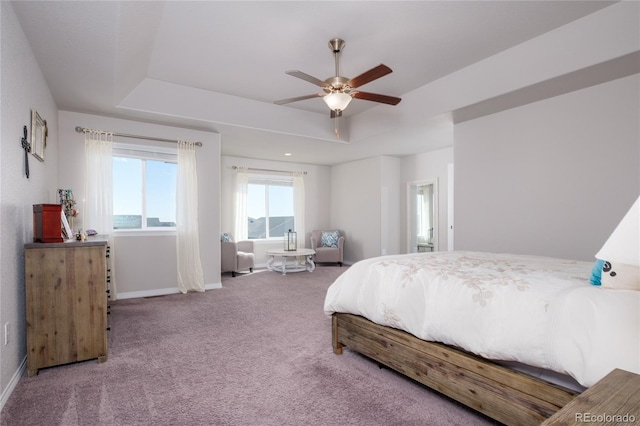 bedroom with carpet floors, a tray ceiling, baseboards, and a ceiling fan