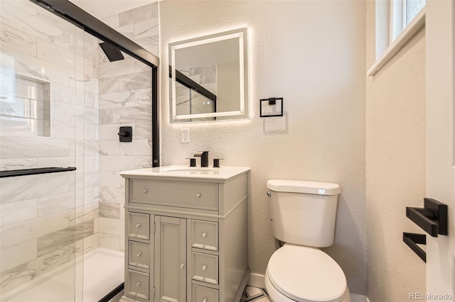 full bath with toilet, a stall shower, vanity, and a textured wall