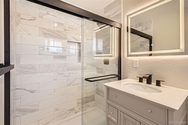 bathroom with vanity, a shower stall, and a textured wall