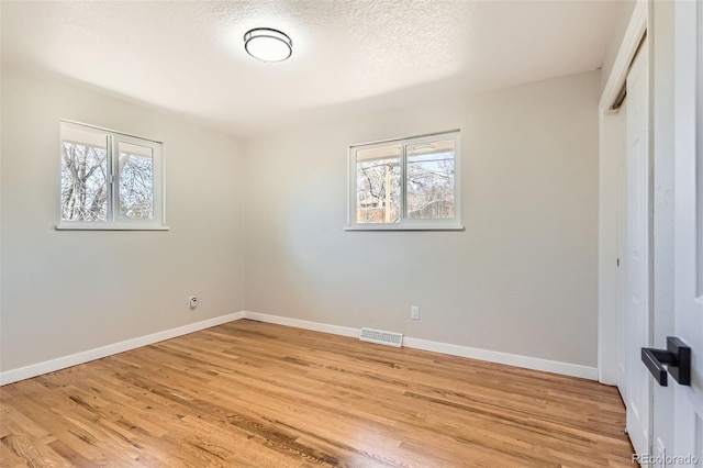 unfurnished bedroom featuring visible vents, multiple windows, and light wood-style floors