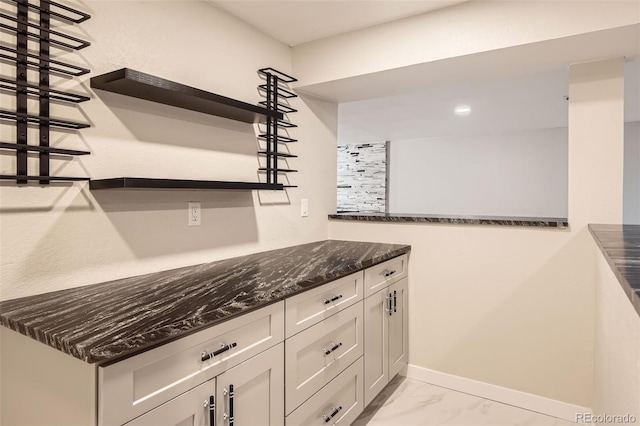 kitchen with baseboards, dark stone counters, marble finish floor, white cabinetry, and open shelves