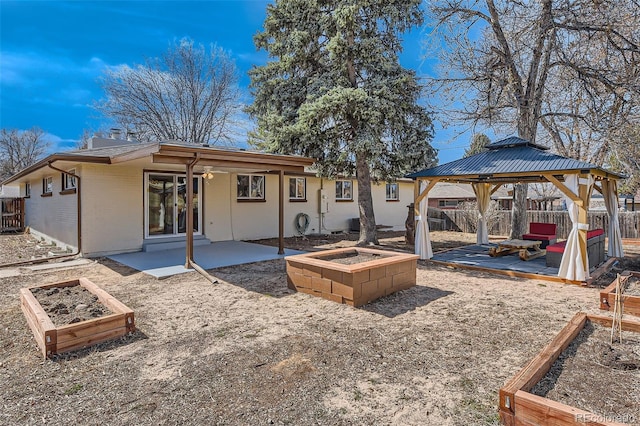 back of property with a patio, a fenced backyard, a gazebo, a vegetable garden, and brick siding