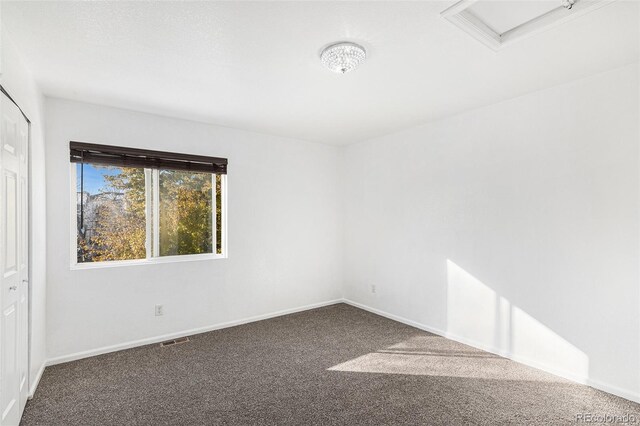 spare room featuring dark colored carpet