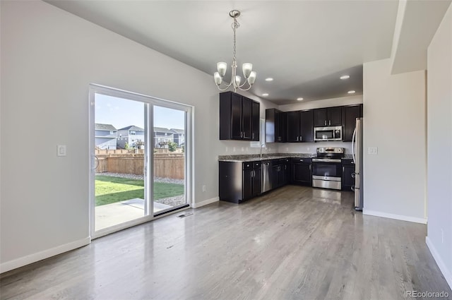 1464 Moraine Valley Dr, Severance, CO 80550 - kitchen featuring stainless steel appliances, a chandelier, light wood-style flooring, dark cabinets, and recessed lighting