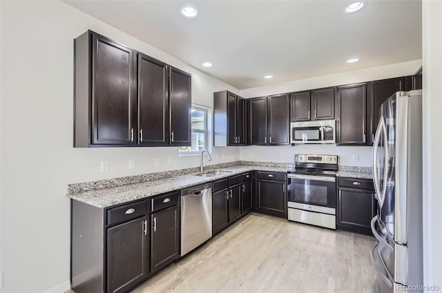 1464 Moraine Valley Dr, Severance, CO 80550 - kitchen featuring stainless steel appliances, light wood-style floors, recessed lighting, light stone countertops, and dark brown cabinetry