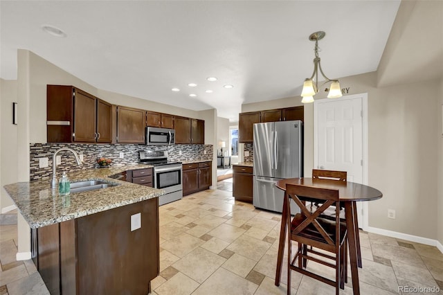 5415 Spruce Ave, Castle Rock, CO 80104 - kitchen featuring appliances with stainless steel finishes, decorative backsplash, a peninsula, stone tile floors, and light stone countertops