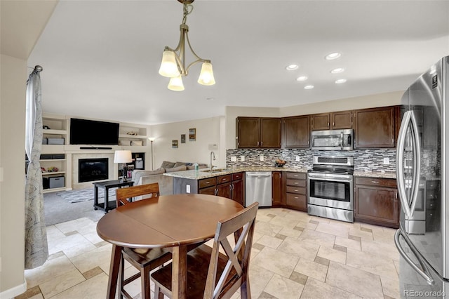 5415 Spruce Ave, Castle Rock, CO 80104 - kitchen with appliances with stainless steel finishes, a glass covered fireplace, decorative backsplash, a chandelier, and hanging light fixtures