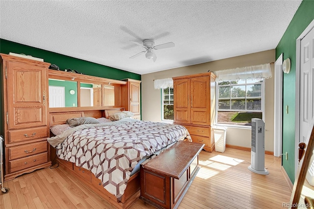 bedroom with ceiling fan, a textured ceiling, and light hardwood / wood-style flooring