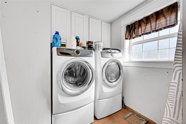 laundry room featuring washing machine and dryer, light tile patterned floors, and cabinets