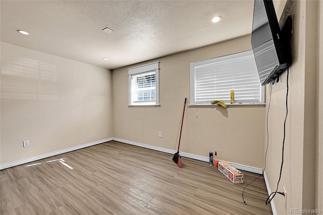 exercise room with light hardwood / wood-style floors and a textured ceiling