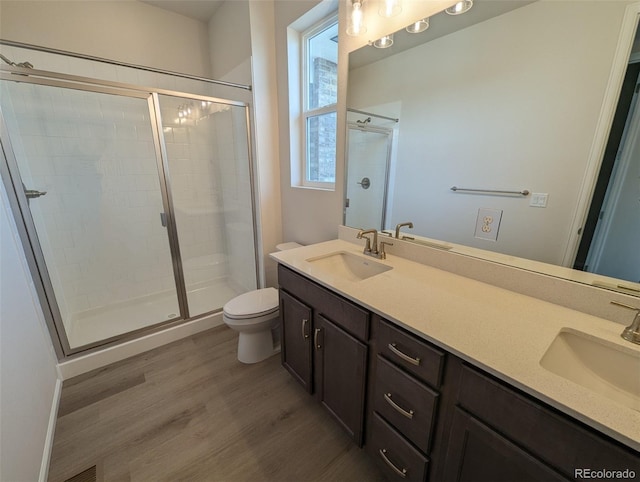 bathroom featuring wood-type flooring, vanity, toilet, and walk in shower