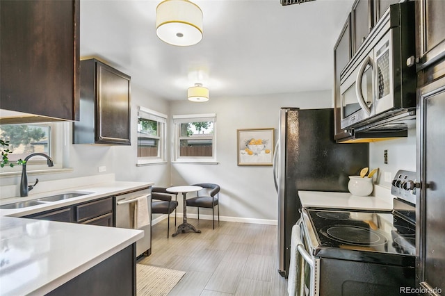 1060 S Harrison St, Denver, CO 80209 - kitchen with stainless steel appliances, dark brown cabinetry, light countertops, and light wood-style flooring