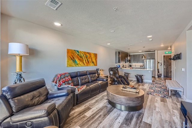 living room with light wood-type flooring and a textured ceiling