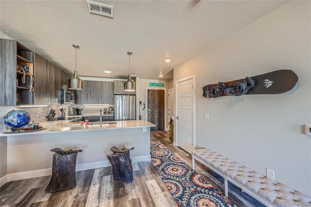 kitchen featuring appliances with stainless steel finishes, dark brown cabinets, a kitchen breakfast bar, sink, and kitchen peninsula