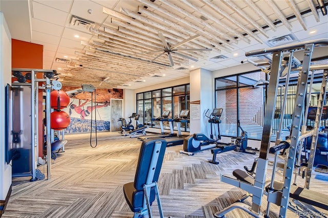 workout area featuring light carpet and a paneled ceiling