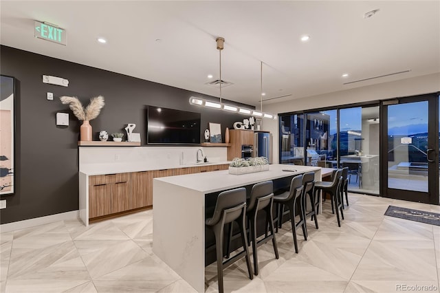 kitchen with a breakfast bar, a spacious island, decorative light fixtures, sink, and light parquet floors