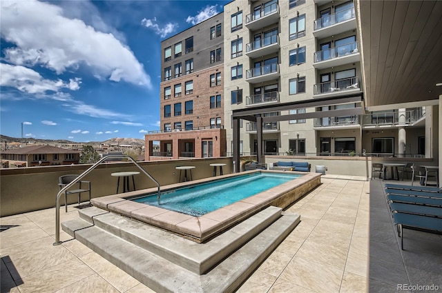 view of swimming pool with a patio area, a mountain view, and a hot tub