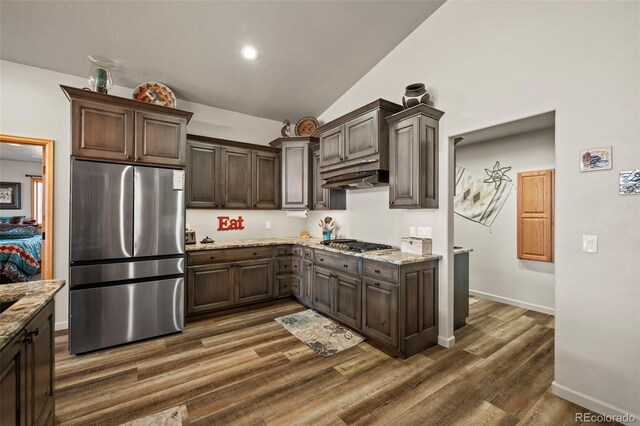 kitchen featuring lofted ceiling, dark brown cabinets, stainless steel appliances, and dark hardwood / wood-style flooring