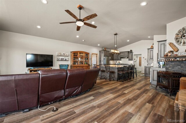 living room with ceiling fan with notable chandelier, lofted ceiling, and dark hardwood / wood-style flooring