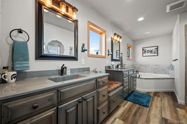 bathroom with wood-type flooring, a bathtub, and vanity