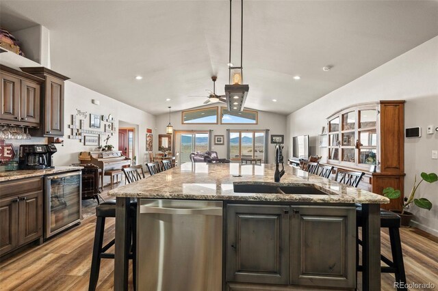 kitchen featuring a breakfast bar area, beverage cooler, a kitchen island with sink, and stainless steel dishwasher