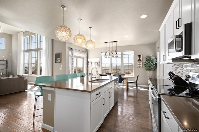 15194 W Washburn Ave, Lakewood, CO 80228 - kitchen with appliances with stainless steel finishes, a chandelier, a breakfast bar, dark wood-style flooring, and recessed lighting