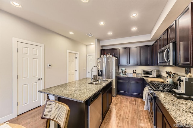 16057 E 47th Pl, Denver, CO 80239 - kitchen featuring appliances with stainless steel finishes, a sink, light wood-style floors, light stone counters, and recessed lighting