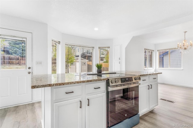 524 Rider Ridge Dr, Longmont, CO 80504 - kitchen featuring an inviting chandelier, electric range, white cabinets, light stone countertops, and light wood-style floors